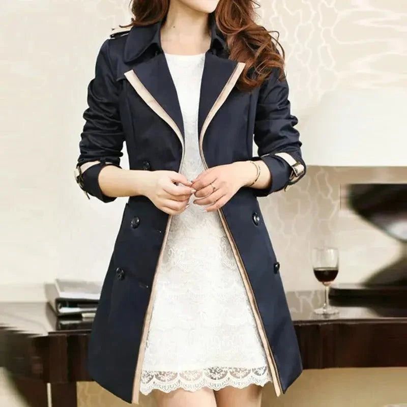 Women's double-breasted long trench coat by TrendLux Wear, shown in a stylish outerwear image with classic design and belt detail.